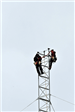 Two Workers at the Top of a Segment of Yonkers Tower Mid-Construction